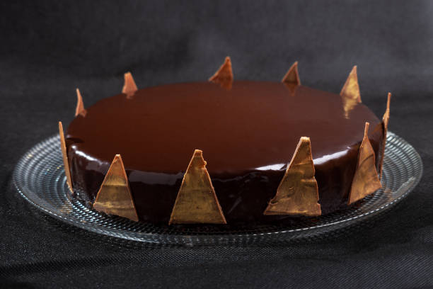 istock Homemade mousse cake with mirror chocolate coating decorated with chocolate triangles painted with edible gold, concept of lactose-free homemade dessert 1363484992