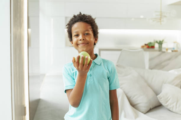 istock Child boy holding an apple at home on white background 1363485154