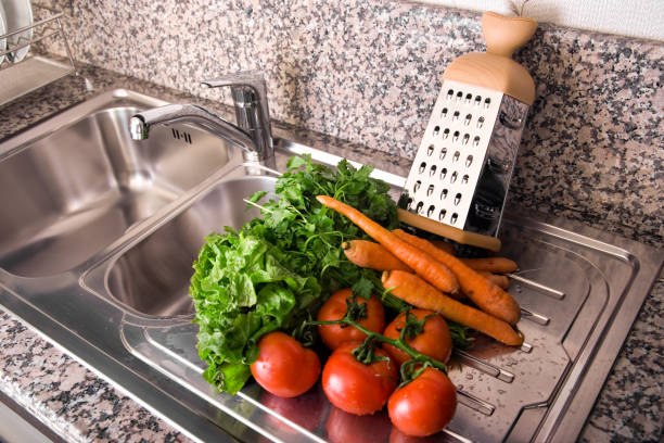 Close up washed clean vegetables on kitchen counter by sink in modern domestic kitchen