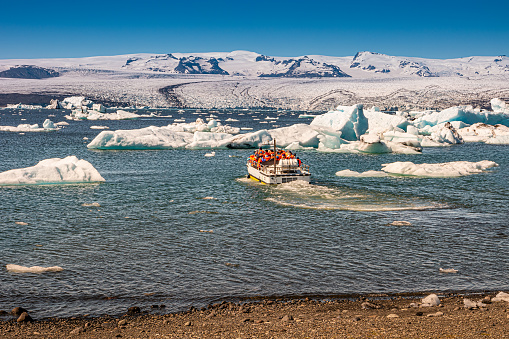 View of Glacier Lagoon with icebergs and zodiac touristic boats for the lake tour, Jokulsarlon, Iceland, summer time