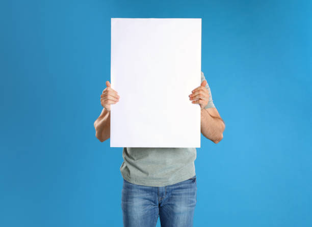 istock Man holding blank poster on blue background 1363489009