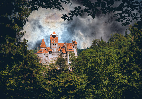 Bran, Transylvania, Romania - June 06, 2021: forest view of the medieval Bran Castle in Transylvania, Romania. The famous mystical tourist attraction, the residence of the legendary Vlad the Impaler, the fairy-tale vampire of Count Dracula