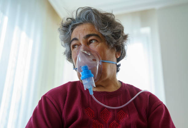 istock Senior woman doing inhalation through oxygen mask at home 1363489282