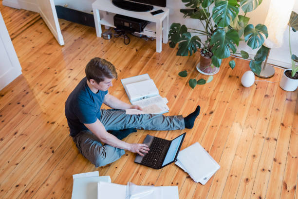 Young man managing household budget online using laptop stock photo