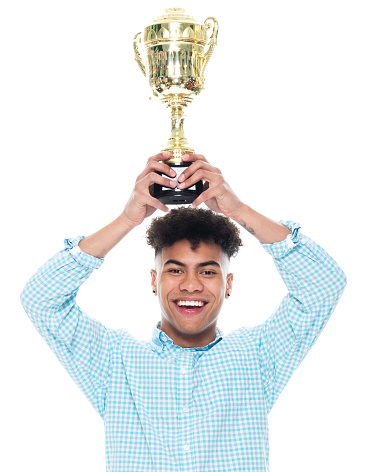 One person of aged 18-19 years old with black hair african-american ethnicity male standing in front of white background wearing shirt who is successful and winning and showing award who is in first place and holding trophy