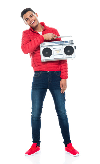 Front view of aged 20-29 years old with black hair african-american ethnicity young male standing in front of white background wearing shirt who is listening and holding boom box
