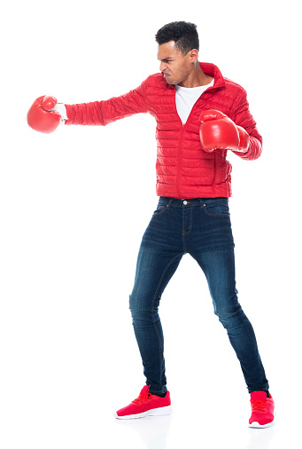 Front view of aged 20-29 years old with short hair african ethnicity male standing in front of white background wearing boxing glove who is showing cool attitude and boxing who is punching