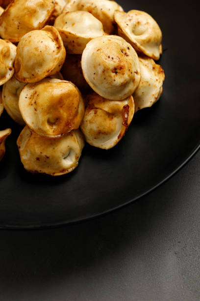 istock Fried dumplings on a black plate. Russian dish. Dumplings. On a black plate and a black background 1363509166
