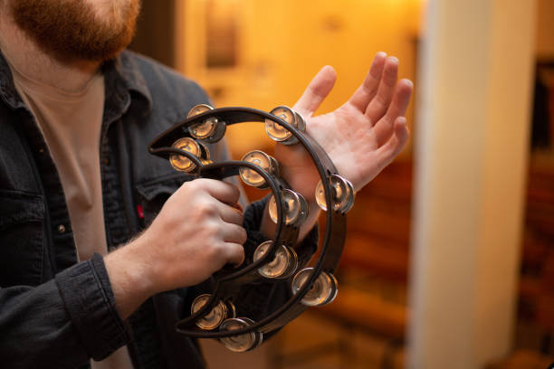 A young guy with a beard plays the tambourine A young guy with a red beard plays the tambourine guiro stock pictures, royalty-free photos & images
