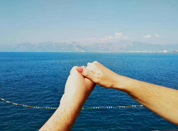 pareja enamorada hombre y mujer tomados de la mano sobre el fondo del mar - honeymoon beach couple heterosexual couple fotografías e imágenes de stock