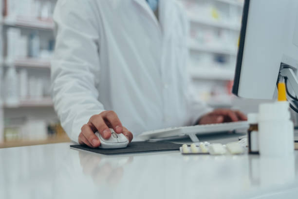 Close shot of pharmacist working in a pharmacy while using a computer stock photo
