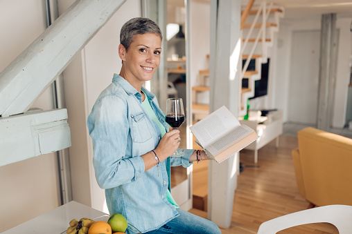 Mid adult woman reading a book and relaxing at home