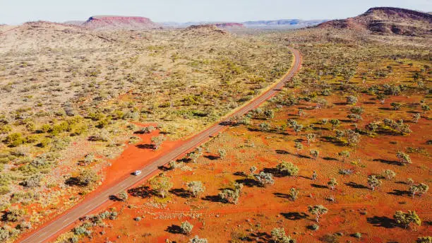 Aerial view of camper van driving along the red scenery of Karijini, WA