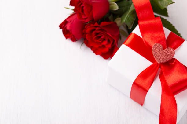 istock White gift box red ribbon and roses on white background 1363538052