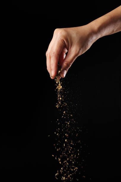 istock Hand sprinkling oregano on black background 1363548071