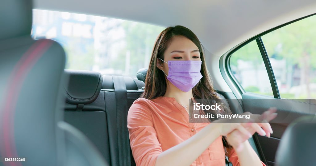 businesswoman use alcohol spray asian successful businesswoman wearing face mask use alcohol spray on hands while commuting in the taxi 20-29 Years Stock Photo