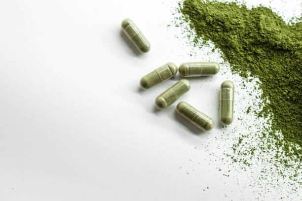 istock Green powder with green capsules on white background. 1363554265