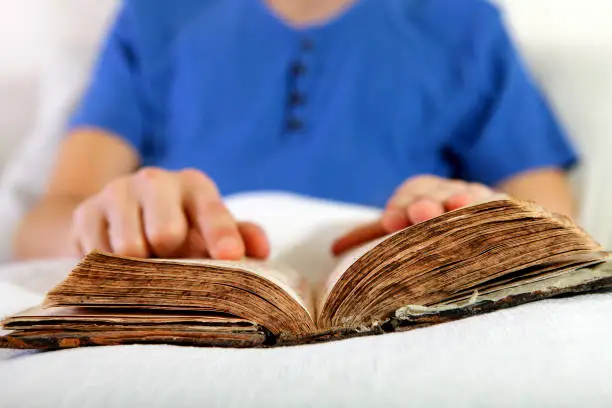 Person with a Bible in the Bed at the Home closeup
