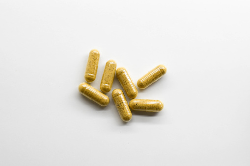 Yellow capsules on white background. Herbal capsules.
