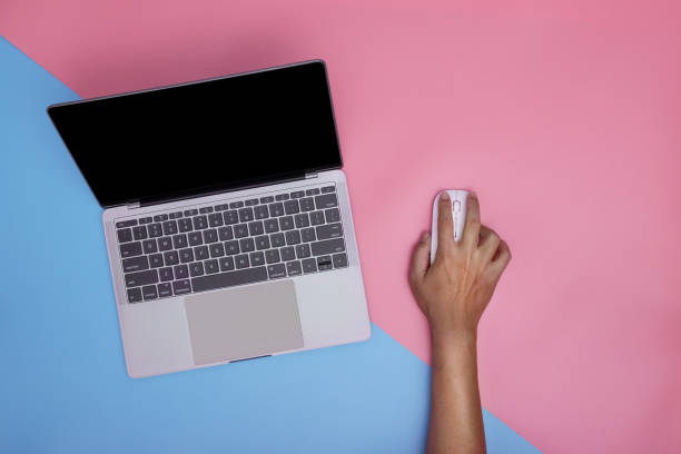 istock Man using laptop and wireless mouse on pink and blue background. copy space. 1363556207