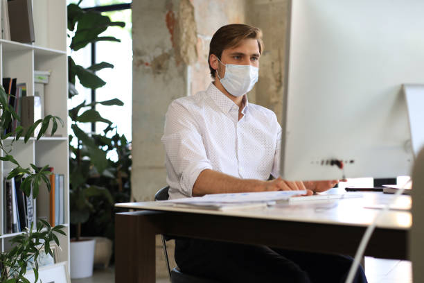 istock Businessman is working in preventive medical mask in office. 1363560247