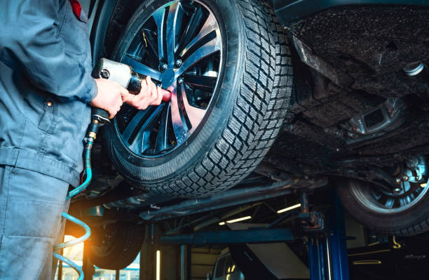 Tires fitting at the car service station. Mechanic removes the wheel using an electric drill. Automobile stands on the car lift. stock photo