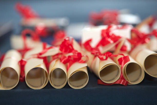 rouleaux de récompenses décorés de rubans rouges - diploma certificate rolled up paper photos et images de collection