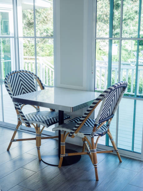 istock Two empty modern rattan chairs with a black and white striped pattern and an empty dining table near the glass door in the restaurant, vertical style. 1363568598
