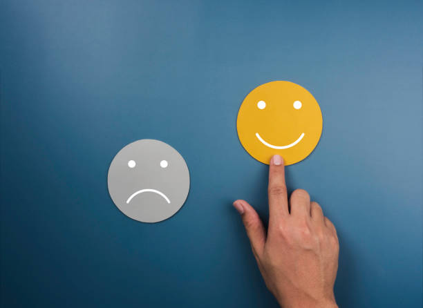 istock Customer service evaluation, ratings, feedback, client experience, satisfaction survey concepts. Happy smile on yellow face chosen by customer's hand near sad face on blue background, minimal style. 1363568599