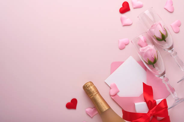 istock Valentines day greeting card with champagne bottle, gift box, red ribbon and envelope with blank note mockup inside on pink background. Top view with space for greetings. Greeting card with copy space 1363572402