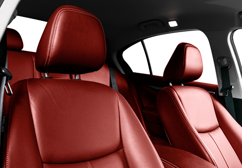 Luxury car red leather interior. Part of leather car seat details with stitching. Comfortable perforated red leather seats. Red perforated leather. Car inside