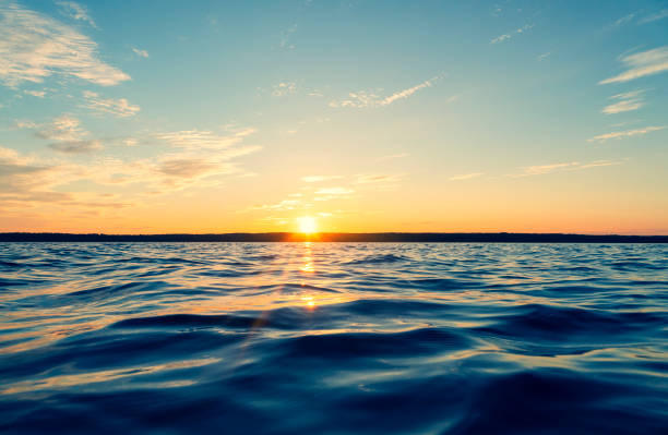 Water surface. View of a Sunset sky background. Dramatic gold sunset sky with evening sky clouds over the sea. View of a Crystal clear sea water texture. Landscape. Small waves. Water reflection stock photo