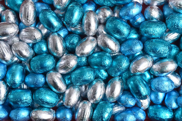 istock Blue,  silver and turquoise foil wrapped chocolate easter eggs, against a black background. 1363573696