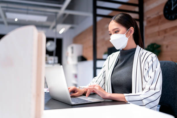 istock attractive asian female sweater working while wearing protective virus mask working in co woking space that have plastic partition social distancing for seat new normal lifestyle 1363575422