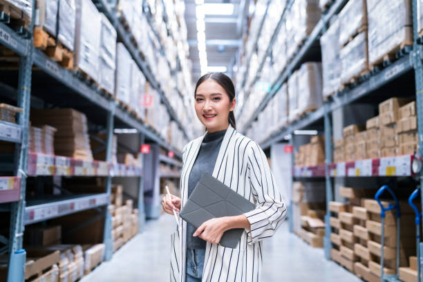 Portrait of asian woman business owner using digital tablet checking amount of stock product inventory on shelf at distribution warehouse factory.logistic business shipping and delivery service stock photo
