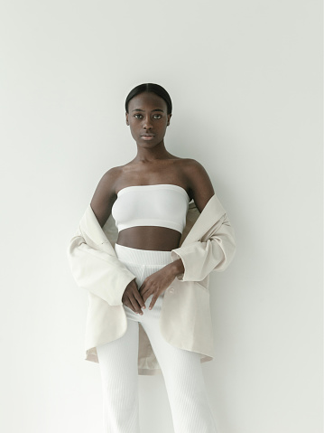 Waist up portrait of beautiful young african girl wearing white crop top jacket and pants. Looks fresh and lovely Fashion model studio portrait on white background Korean style fashion Beauty Fitness Healthcare concept