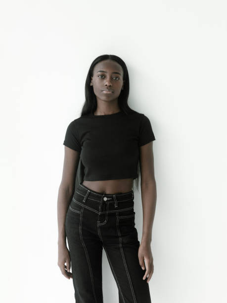 ritratto bella giovane ragazza africana che indossa crop top nero e jeans in posa su sfondo bianco - bassiera foto e immagini stock