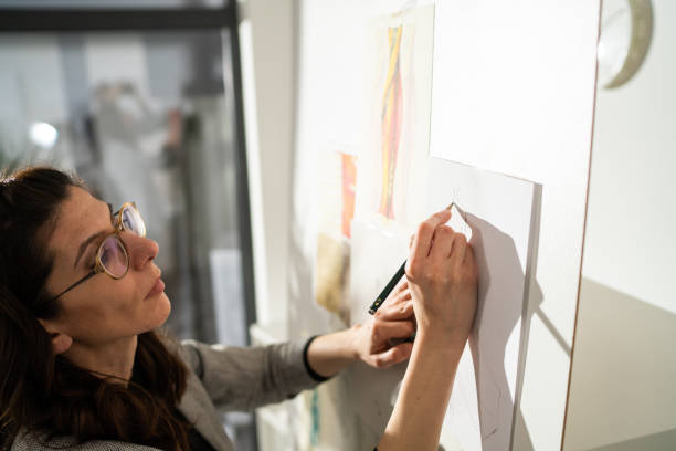 istock Female tailor standing in studio and drawing new dress 1363581681