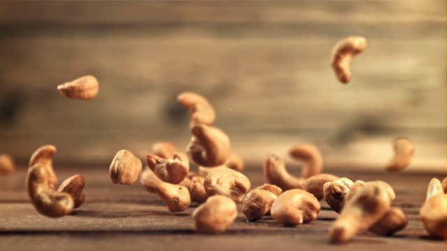 Cashew nuts fall on the table. Filmed is slow motion 1000 frames per second.