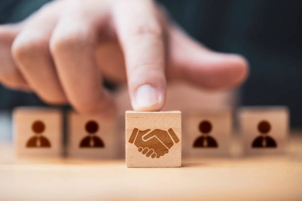 Hand putting hand shaking which print screen on wooden cube block  in front of human icon for business deal and agreement concept. Hand putting hand shaking which print screen on wooden cube block  in front of human icon for business deal and agreement concept. coordination stock pictures, royalty-free photos & images