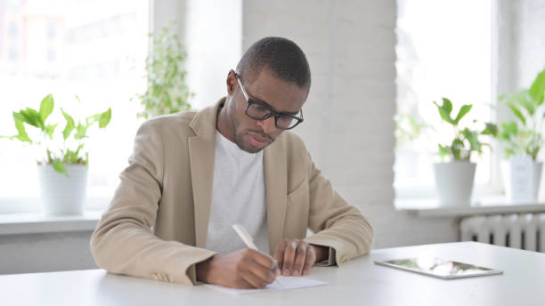 istock African Man Writing on Paper in Office 1363584011