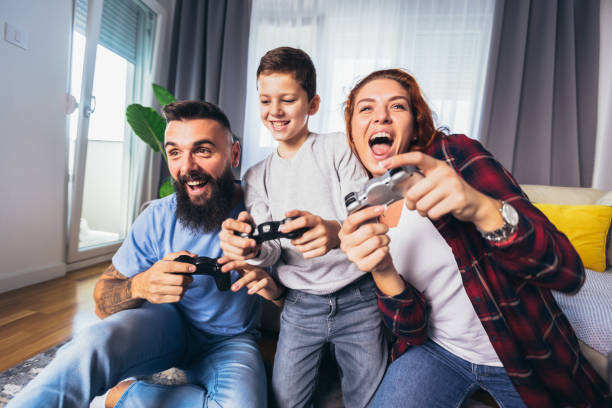 Happy family playing video games at home and having fun together. stock photo