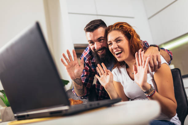 istock Young couple in love drinking wine in house kitchen and using laptop. 1363585010