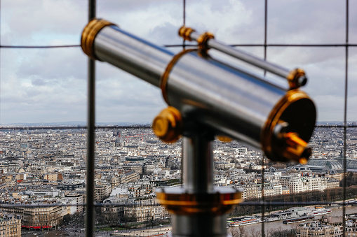 In the foreground a coin operated telescope in the background a view of the city of Paris, France
