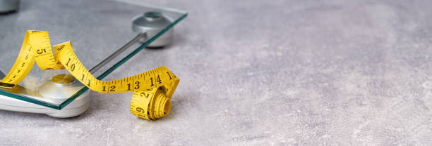 istock yellow tape measure on glass bathroom scale 1363586390