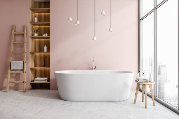 istock Light bathroom interior with bathtub, shelf rack and window with city view 1363586415