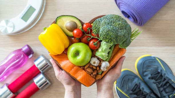 estilo de vida saudável na dieta cetogênica, comendo keto alimentos limpos boa saúde dieta em prato cardíaco com exercício corporal aeróbico, aula de treinamento de ginástica, escala de peso e sapatos esportivos em fitness center - diabetes - fotografias e filmes do acervo