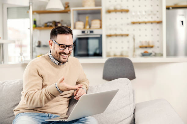 A happy man sitting at cozy home and showing at laptop. A happy man sitting at cozy home and showing at laptop. job retraining stock pictures, royalty-free photos & images