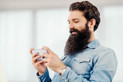 A happy bearded man using his phone, flirting with girl.