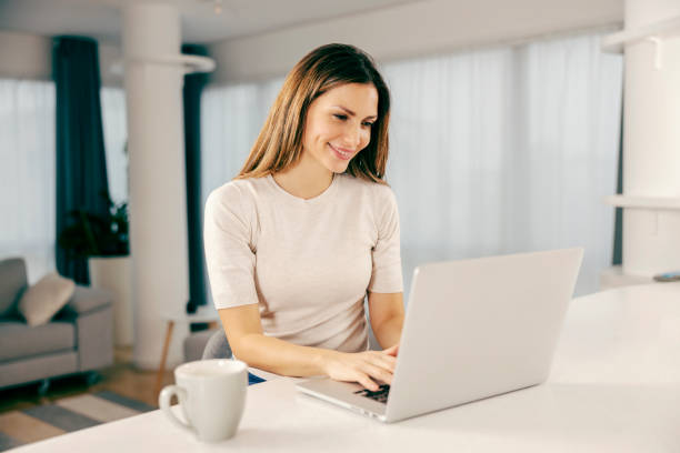 istock A happy woman using a laptop in kitchen at her home. 1363592746
